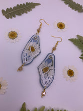 Load image into Gallery viewer, Daisy wing earrings with blue background
